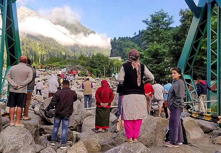 People stand near debris after flash floods triggered by cloud burst, near Manali, Thursday, July 25 - PTI